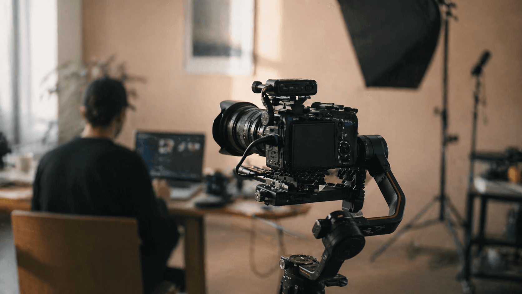 Sony FX3-Kamera auf einem Gimbal-Stabilisator während eines Drehs, Crew-Mitglied am Laptop im Hintergrund.